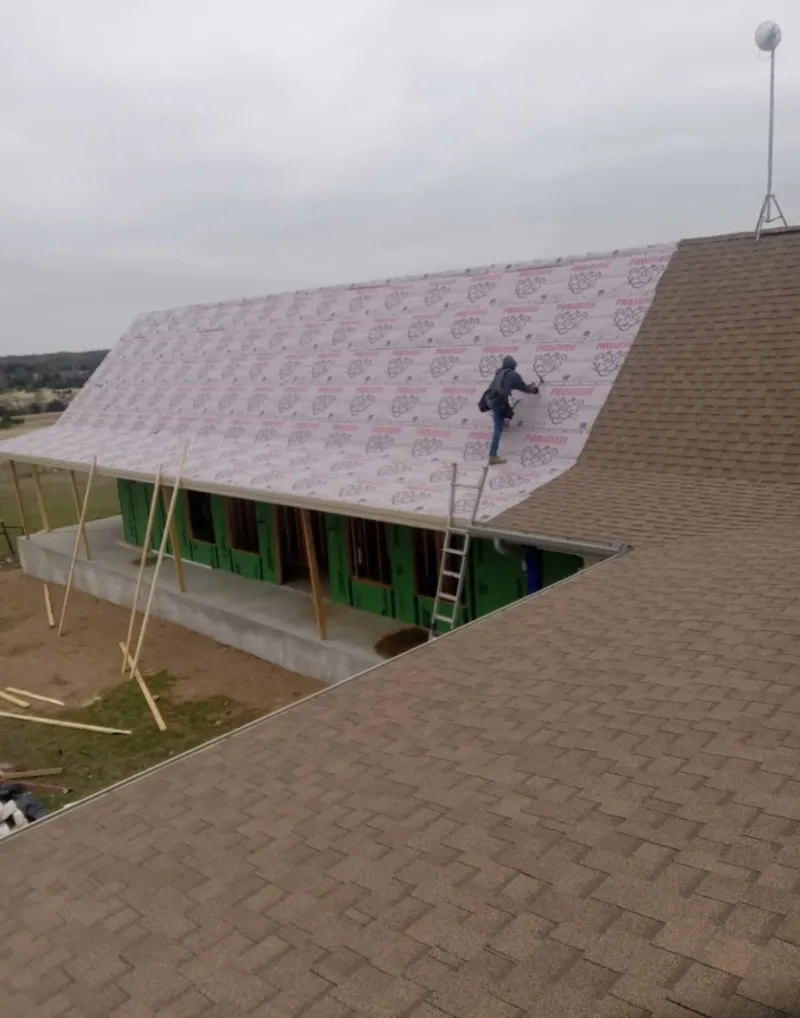 Worker preparing underlayment for a metal roof installation in Marysville
